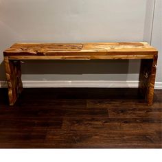 a wooden bench sitting on top of a hard wood floor next to a white wall