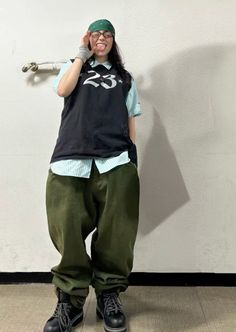 a person standing in front of a wall talking on a cell phone and wearing green pants