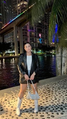 a woman standing on the sidewalk in front of some water