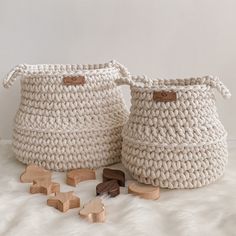 two crocheted baskets sitting on top of a white fur covered floor next to wooden blocks