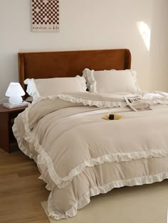 a bed with white ruffled sheets and pillows