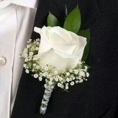 a white rose and baby's breath boutonniere on a man's lapel