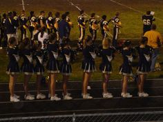 a group of cheerleaders standing on the sidelines