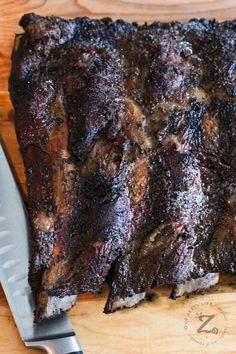 a large piece of meat sitting on top of a cutting board next to a knife