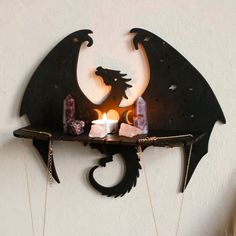 a wall mounted shelf with candles and other items on it's sides, in the shape of a dragon