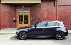 a black car parked in front of a brick building