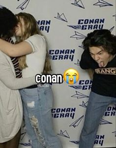 two people are hugging each other in front of a wall with the words conan on it