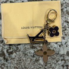 a louis vuitton keychain with a flower on it sitting next to a yellow pouch