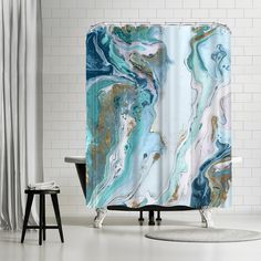 an abstract shower curtain with blue and green marbles on the outside, in front of a white brick wall