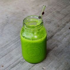 a green smoothie in a mason jar with a straw sticking out of the top