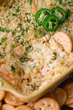 a casserole dish filled with cheese and green bell peppers, surrounded by crackers