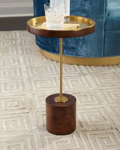 a table with a glass on it and a gold stand in front of the chair