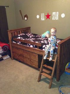 a baby sitting on top of a bed next to a wooden ladder in a room