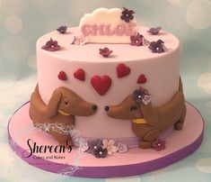 there is a pink cake with two dogs on the top and hearts in the middle