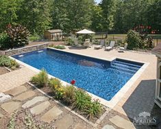 an empty swimming pool surrounded by landscaping and trees in the back yard with patio furniture