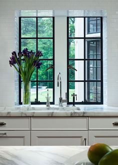 a kitchen with two windows and some flowers in the window sill next to it