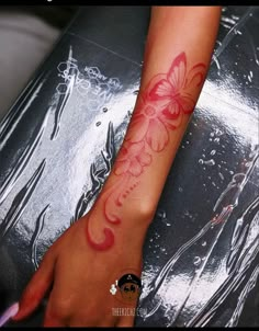 a woman's arm with a red butterfly tattoo on the left side of her arm