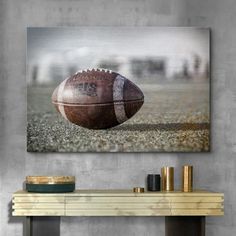 an american football on the field in front of a gray wall