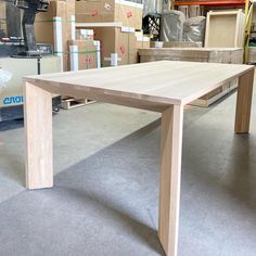 a wooden table sitting on top of a floor next to boxes and other items in a warehouse