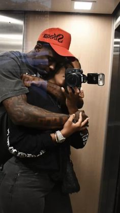 a man and woman hugging in front of a mirror while holding up their cell phones