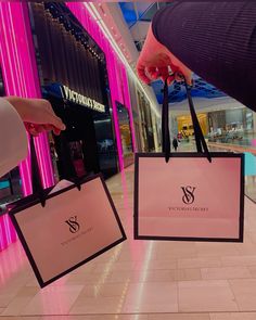 two pink shopping bags being held by someone's hand