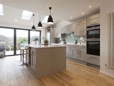 a large kitchen with an island in the middle and two pendant lights hanging from the ceiling