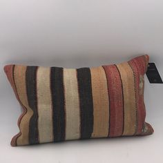 a striped pillow with a tag hanging from the side on a white wall behind it