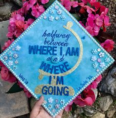 someone is holding up a blue graduation cap with the words, halfway between where i am, and where i'm going