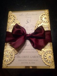 a wedding card with a red bow on the front and gold foilwork around it