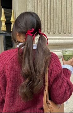 a woman in a red sweater is holding a cup and looking at her cell phone