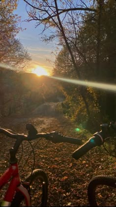 the sun is setting over a dirt path with bicycles parked on it's sides