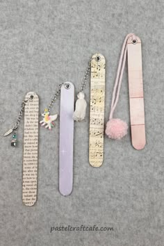 four different types of bookmarks are shown on a gray surface, one has a measuring tape and the other has a tassel