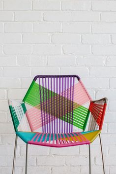 a multicolored chair sitting in front of a white brick wall