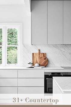 a kitchen with marble counter tops and white cabinets, along with a cutting board on the stove