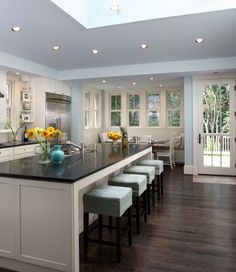 a kitchen with white cabinets and black countertops has sunflowers on the island