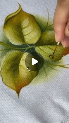 someone is painting a flower on a t - shirt