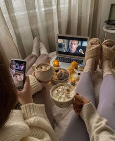 two people sitting on a bed with their feet propped up in front of a laptop