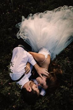 a man and woman laying on the ground in front of each other with their arms around each other