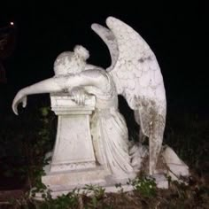 an angel statue sitting on top of a white pedestal