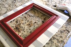 a red frame sitting on top of a counter next to a white and black checkered towel