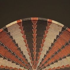 an orange and black woven basket sitting on top of a table