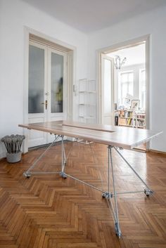 an empty room with a long table in the center and two doors leading to another room