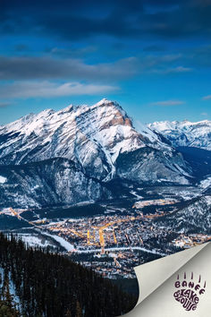 a snowboarder is standing on top of a snowy hill with mountains in the background