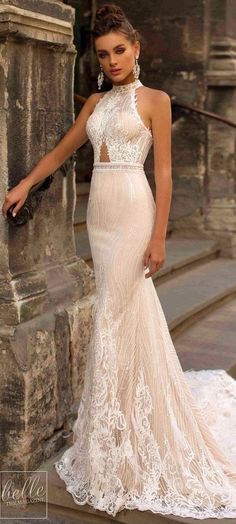 a woman in a wedding dress leaning against a stone wall and posing for the camera