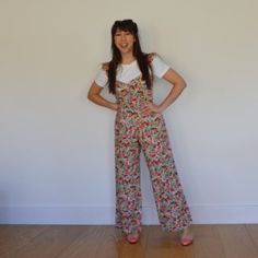 a woman standing in front of a white wall with her hands on her hips and smiling