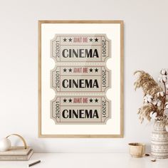 two movie tickets hanging on the wall next to a potted plant and vase with flowers