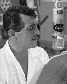 a man sitting in front of a microphone with a bottle of alcohol next to him