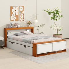 a bed with drawers underneath it in a white and wood bedroom, next to a potted plant