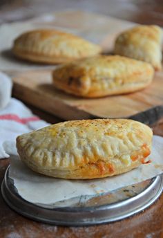 three pastries sitting on top of a wooden cutting board