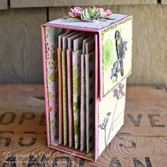 a close up of a small box on a wooden table with flowers and birds in it